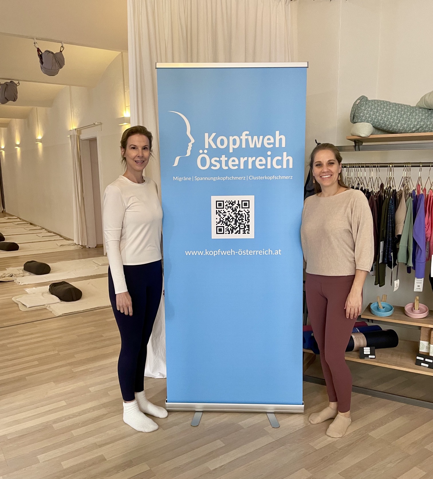 Zwei Frauen neben dem Kopfweh-Österreich-Roll-up im Yogastudio in Wien